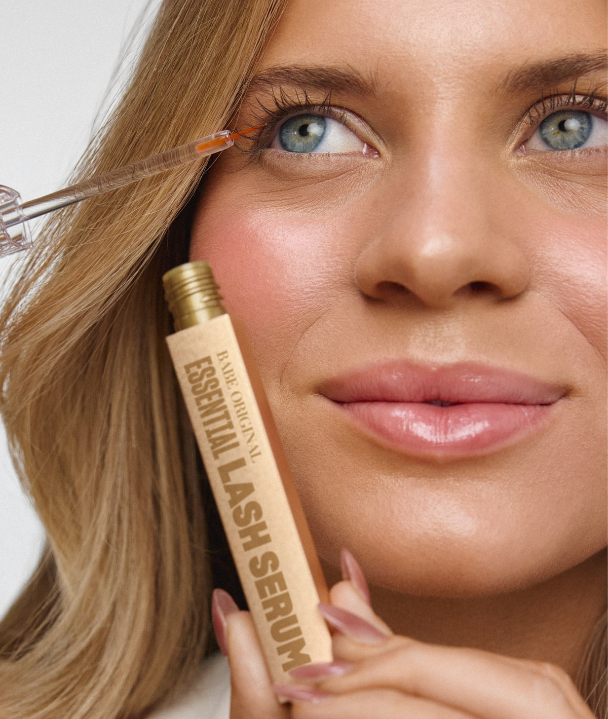 Model applying Essential Lash Serum along the upper lash line